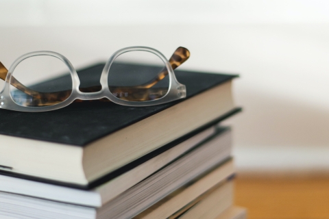 Close up of a pair of glasses on top of a pile of books